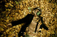 Фотопортрет мужчины в защитном шлеме летчика, лежащего в листве на земле