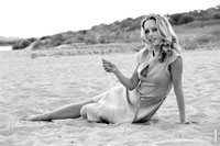 Гламурный фотопортрет девушки в ч/б на песчаном пляже, сидя на песке
