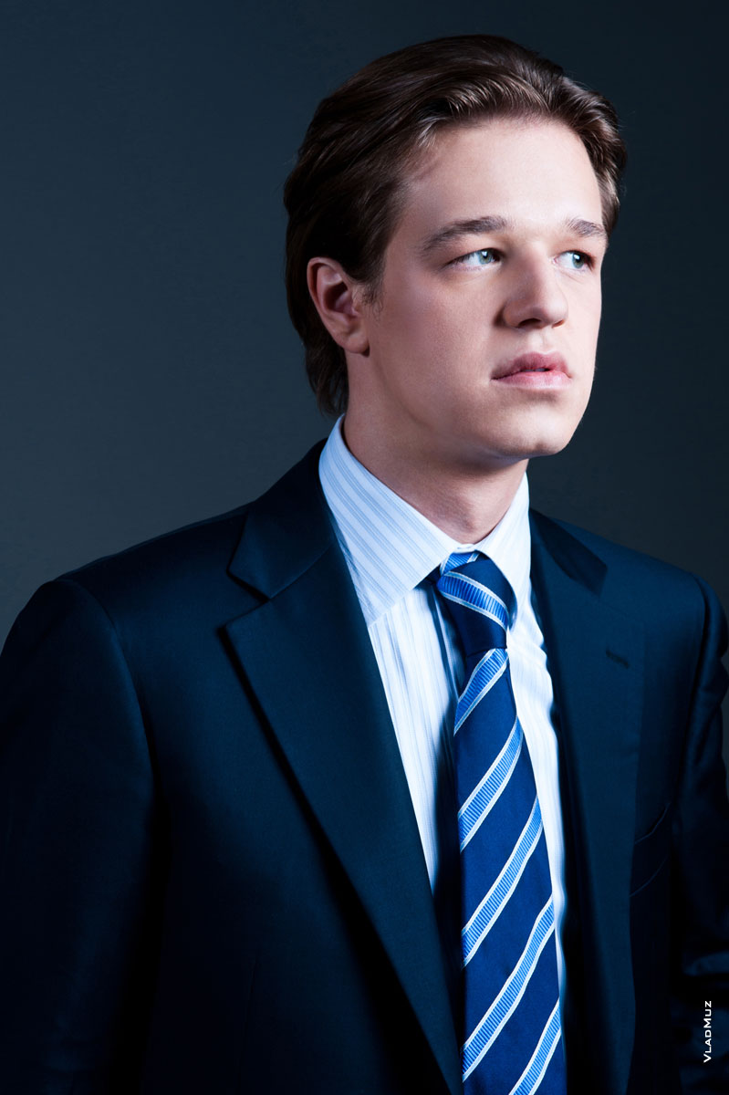 Деловой портрет мужчины в костюме с галстуком в студии на черном фоне. Поясной план