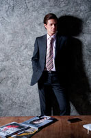 Модный мужской бизнес портрет для делового портфолио. Фото мужчины в студии у стены, перед столом, руки в карманах
