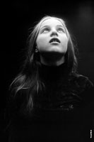 Фотопортрет девочки, смотрящей вверх, на черном фоне в темной тональности