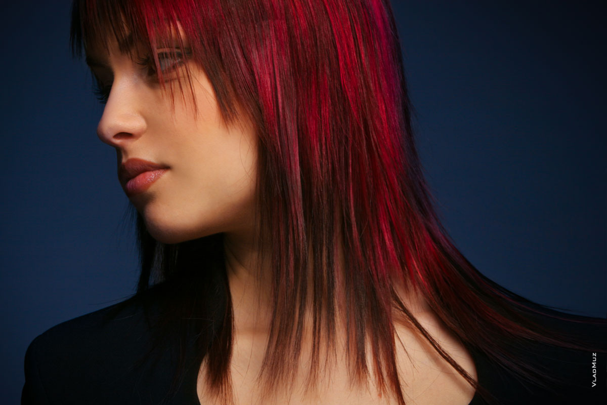Рекламный фотопортрет девушки с яркой прической и красными прядями волос в темной тональности