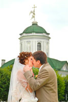 Свадебная фотография с ангелом: фото поцелуя новобрачных на фоне церкви Спаса Всемилостивого в Кускове