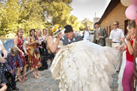 >Фото жениха с невестой на руках перед рестораном под дождем из пшена, конфет и монет
