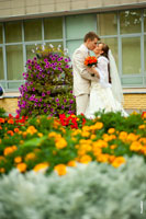 Свадебный поцелуй возле ЗАГСа. Кругом клумбы с цветами