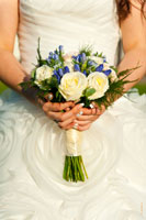 Букет невесты в руках на фоне свадебного платья крупным планом