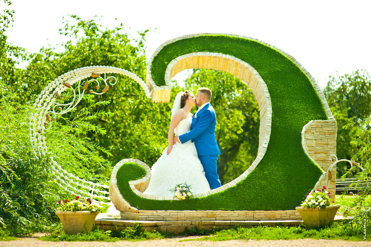 Свадебный поцелуй молодоженов в центре сердечной композиции на Аллее любви в Коломенском