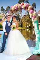 Фото жениха с невестой у свадебной арки во время торжественной регистрации брака