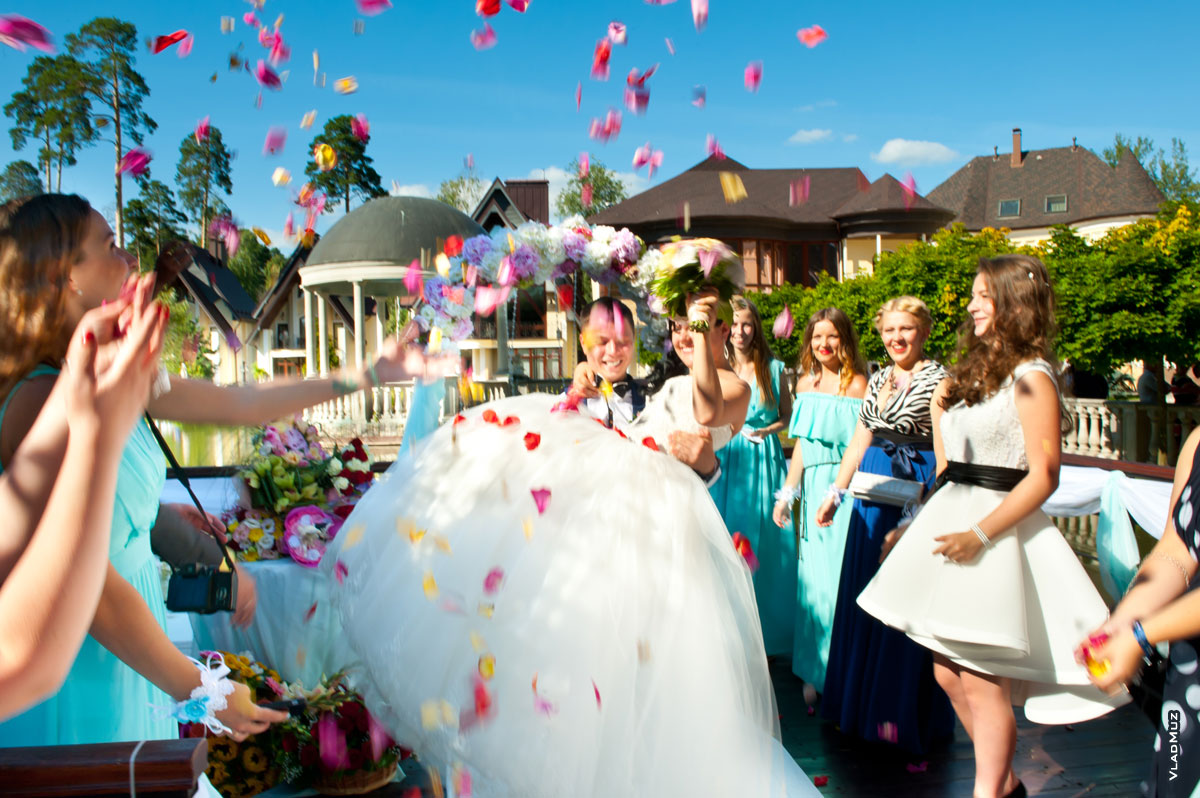 Жених торжественно уносит невесту под салют из лепестков роз после церемонии регистрации брака