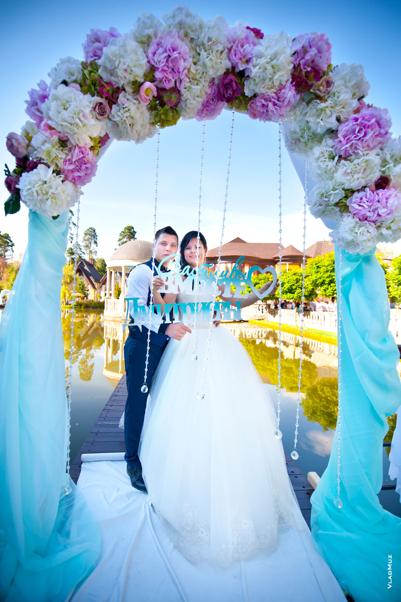 Фото свадебной пары в арке из цветов в холодных тонах