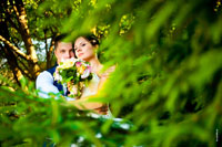 Свадебный фотопортрет жениха и невесты с букетом среди ветвей