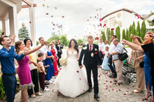 Фото оваций гостей и летящих лепестков роз над женихом и невестой