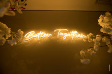 Фото неоновой надписи на английском “Better Together” над женихом и невестой, что переводится, как «лучше вместе»