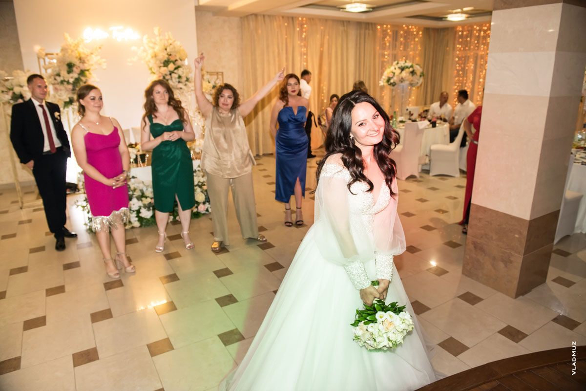 Начало репортажной серии фотографий броска букета невестой: фото невесты с букетом и ее подруг на заднем плане