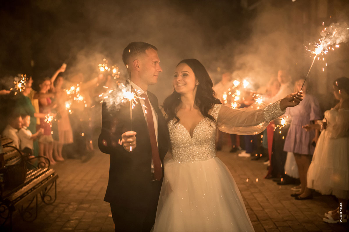 Финальное свадебное фото жениха с невестой с горящими бенгальскими огнями