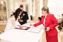 Фото невесты, ставящей подпись в свидетельстве о заключении брака, во время торжественной церемонии регистрации