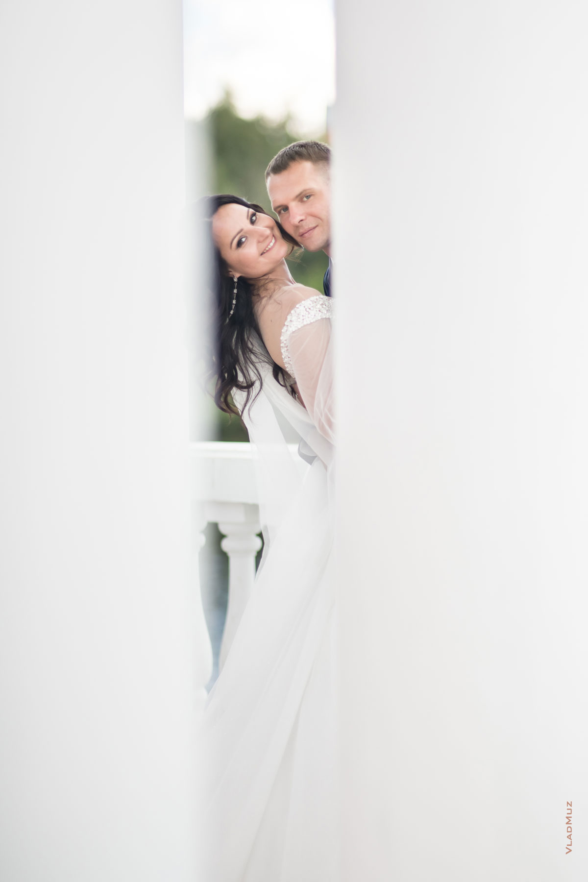 Фото жениха с невестой в расфокусе белых колонн ротонды