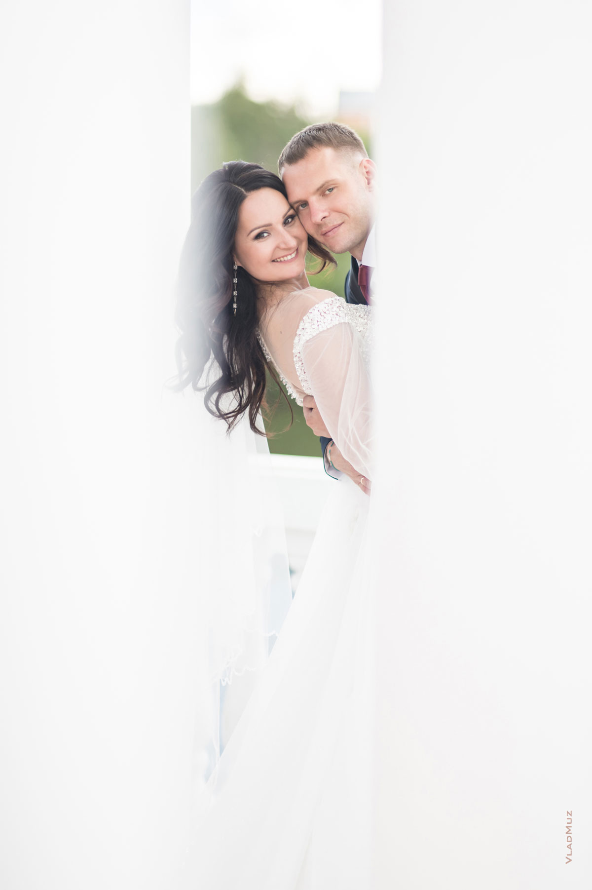 Фото жениха с невестой между белых колонн ротонды