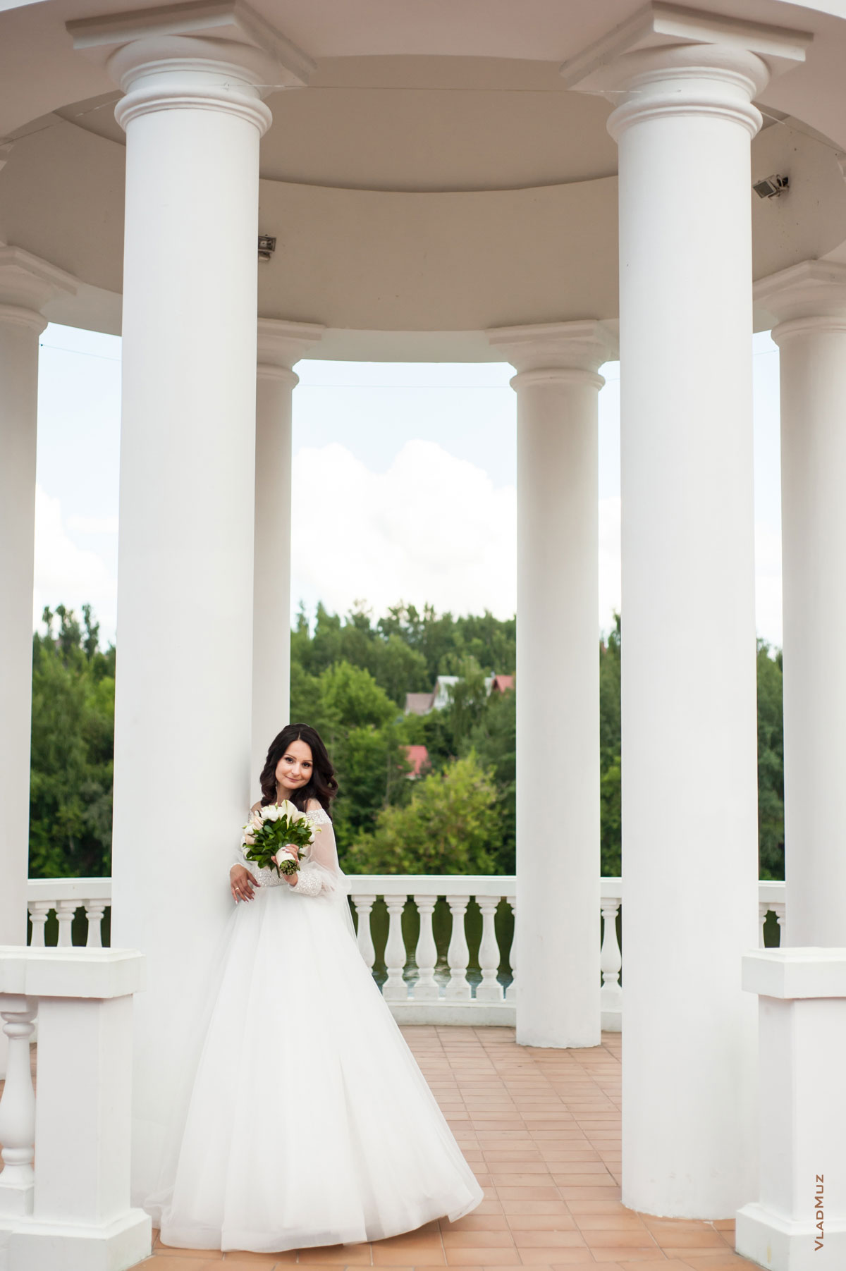 Фото красивой невесты в свадебном платье в полный рост у белой колонны ротонды