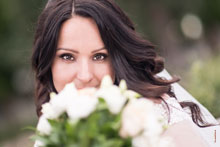 Горизонтальный фотопортрет невесты, с акцентом на глазах, закрывающей лицо букетом