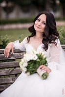 Фотопортрет красивой невесты с букетом, сидя на лавочке