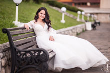 Фото красивой и смеющейся невесты, сидя на лавочке, в полный рост, на набережной комплекса «Белый берег»