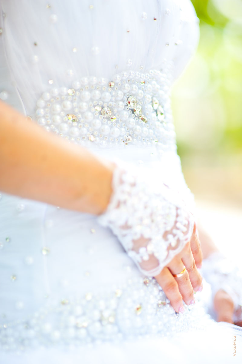 Фото фрагментов свадебного платья и обручального кольца на руке невесты