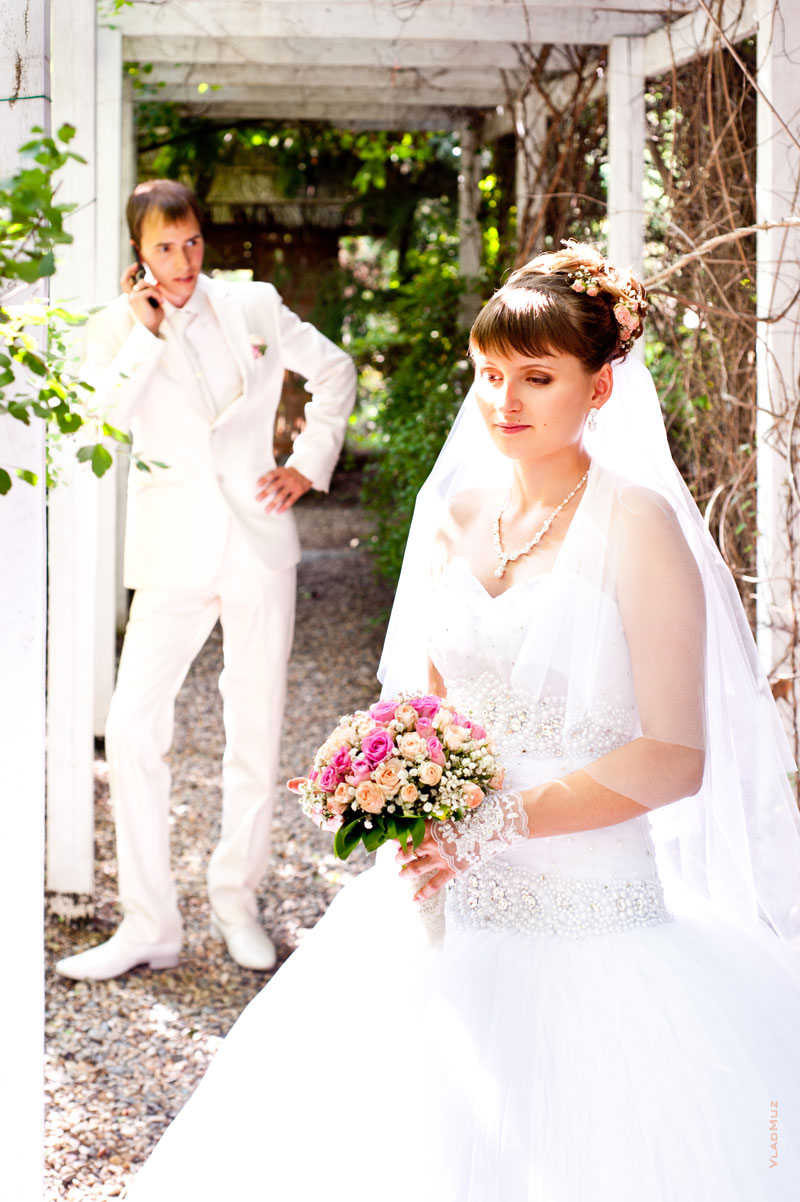 Фото жениха, говорящего по телефону, невеста стоит в ожидании