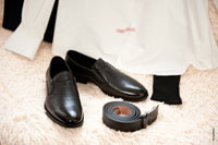 Свадебный натюрморт: черные туфли, ремень, носки и белая рубашка жениха на диване