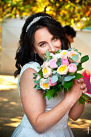 Фотопортрет смеющейся невесты, закрывающейся свадебным букетом