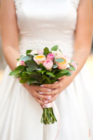 Фото букета в руках невесты на фоне белого свадебного платья