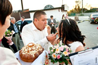 Жених с невестой кормят друг друга в последний раз соленым караваем