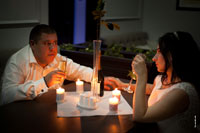 Фото жениха с невестой за столом в кафе с бокалами шампанского при свете свечей