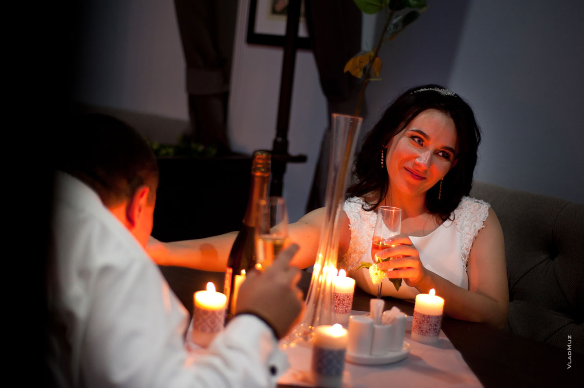 Фото невесты за столом с бокалом шампанского при свете свечей