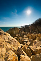 Побережье у Воронцовского парка в Алупке, морской пейзаж: скалистый берег, камни, синее небо, солнце