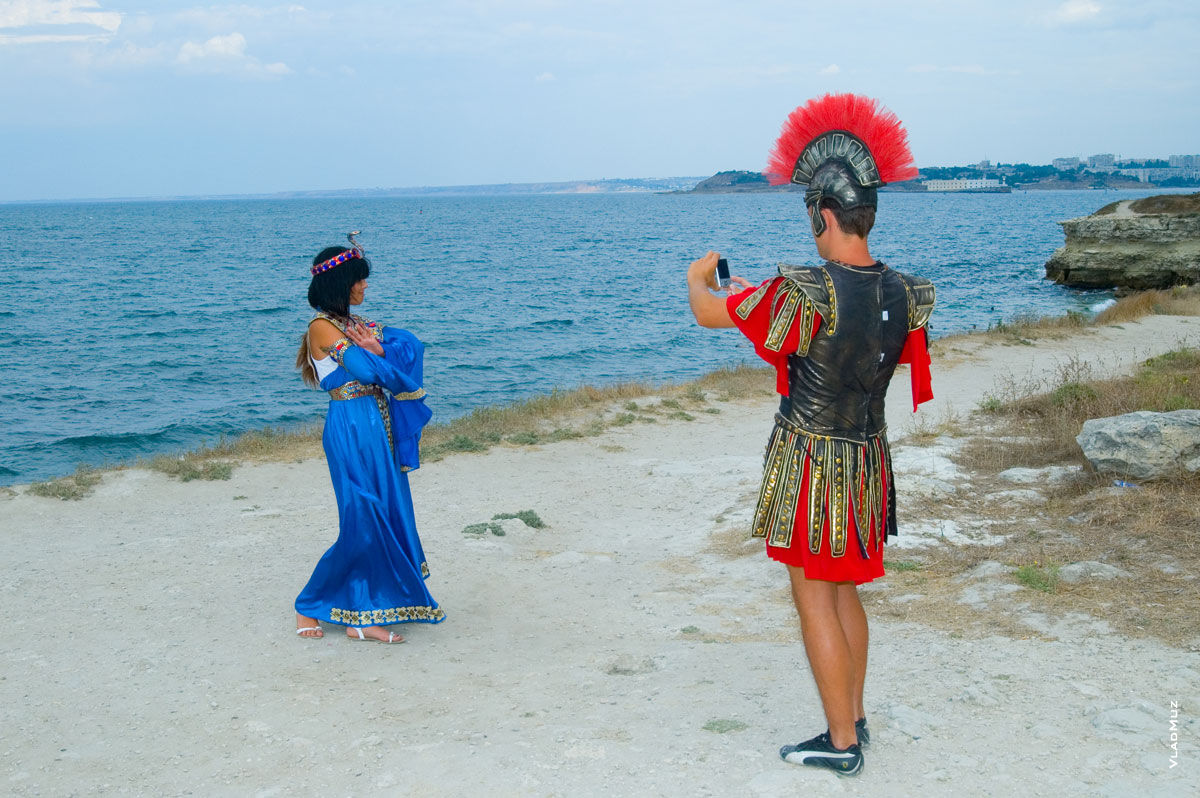 Древнегреческий воин в модных кроссовках фотографирует телефоном свою спутницу