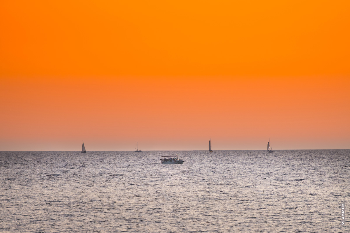 Морской фотопейзаж: катер «Авега» и яхты на горизонте в море после заката