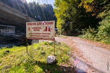 Фото щита с запретом прохода по старому шоссе и предупреждениями об опасности камнепадов и обрывов